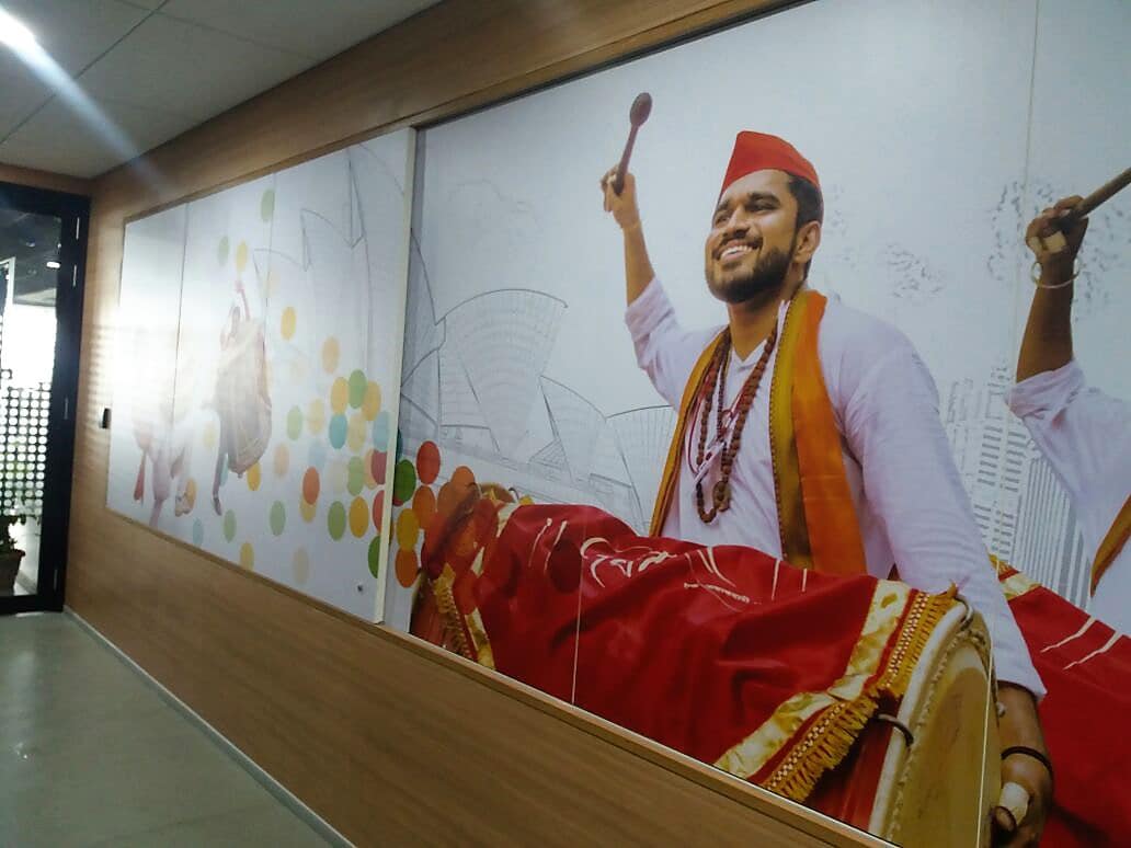 Large-sized custom wallpaper showing a man drumming a dhol. The print is pasted in a corporate office to enhance its interior decor.