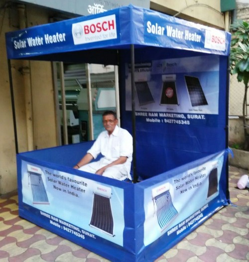 collapsible exhibition booth made of blue canvas stretched on a metal cuboid frame with a man sitting inside
