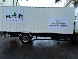 The uneven corrugated side panel of a large container truck is branded using specialised printable vehicle vinyls