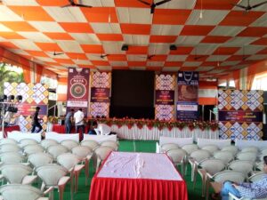 Colorful mandap covering chairs and an elevated stage backdrop with an LED screen in the center