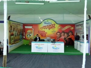 Large exhibition backdrop and side panels showing product images of Chawanprash company with a table in the foreground