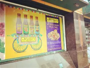 Large glass frontage of a supermarket branded with an ad for products of Mother’s Recipe using dotted film for glass which allows people in the store to see what is happening on the roads