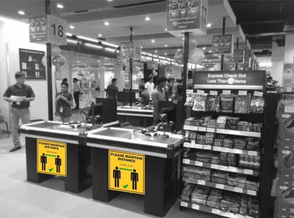 Printed coronavirus safety sign on a cash counter asking people to maintain social distancing