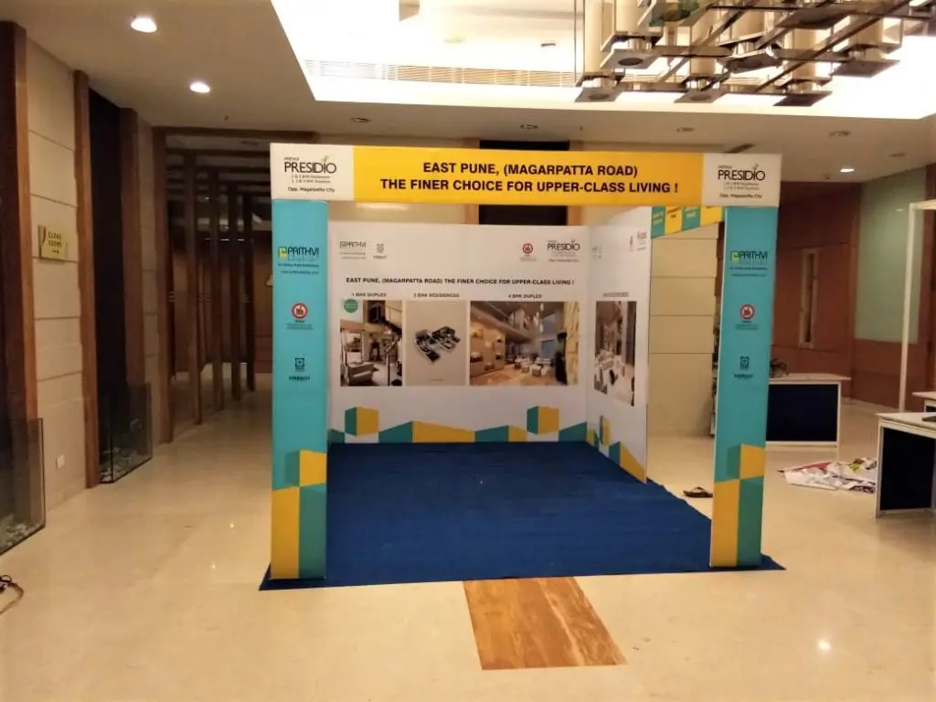 a non-lit 2D arch gate for entrance made of a metal frame with a print stretched on it set in front of an exhibition backdrop in the lobby of a hotel