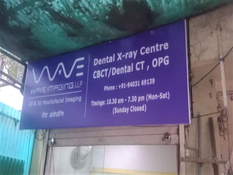 blue colored shop name board flex for wave imaging dental clinic mounted above the shuttered shop front