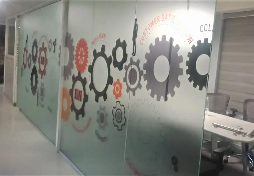 frosted glass film print showing images of gears pasted on the cabin partition of a large office