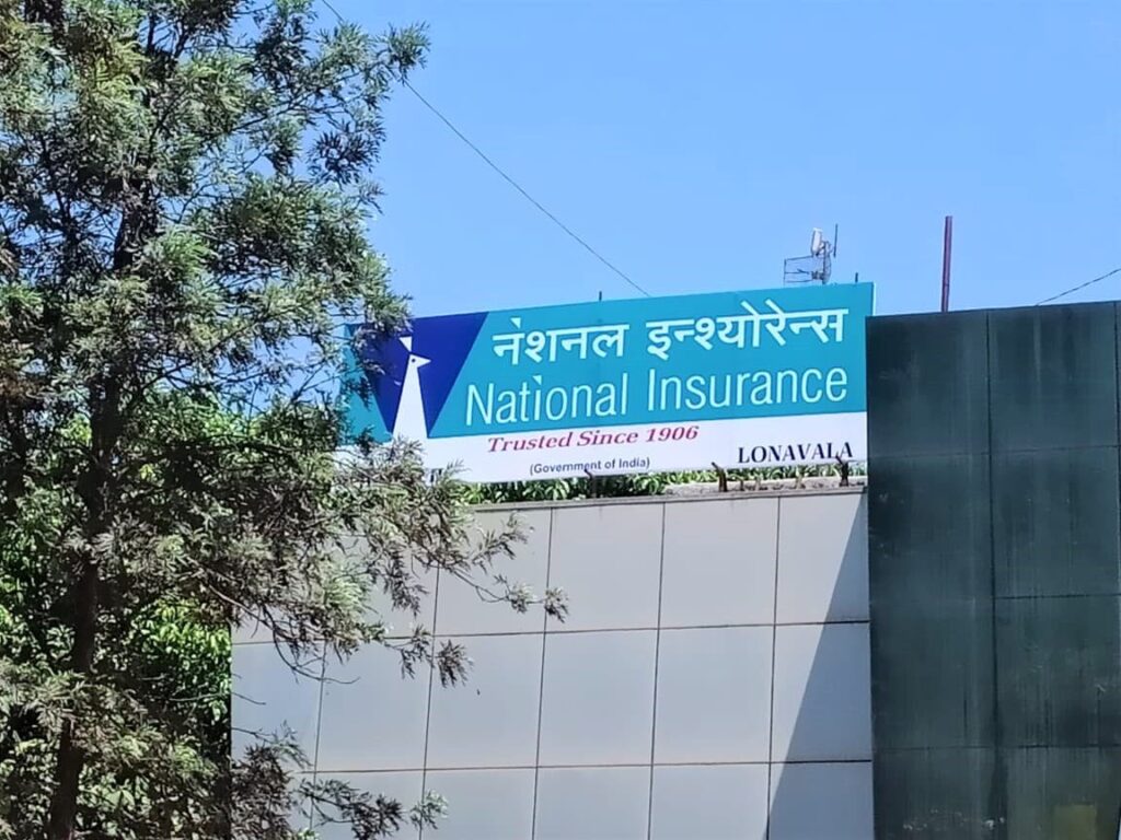 huge frontlit flex sign board for the national insurance academy fitted atop a tall building