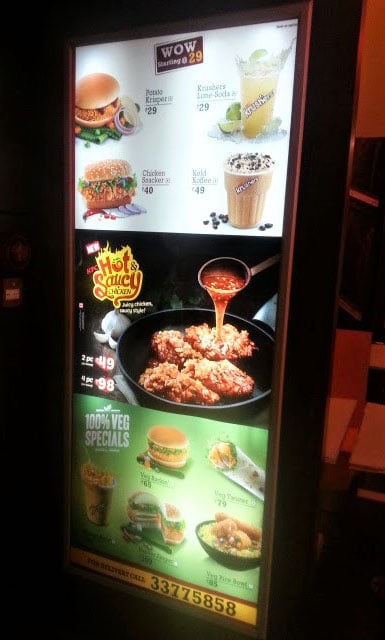 large glowing backlit LED light box installed on a pillar displaying a fast food menu