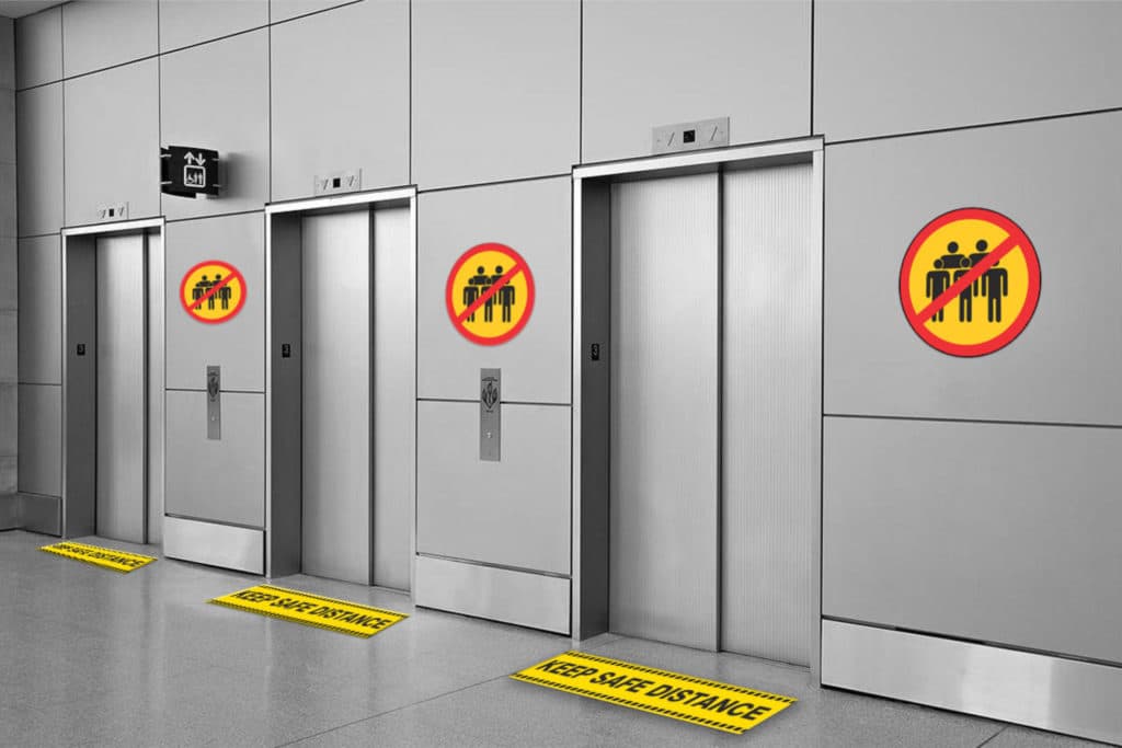 wall and floor stickers asking people to keep distance and avoid crowding in a lift