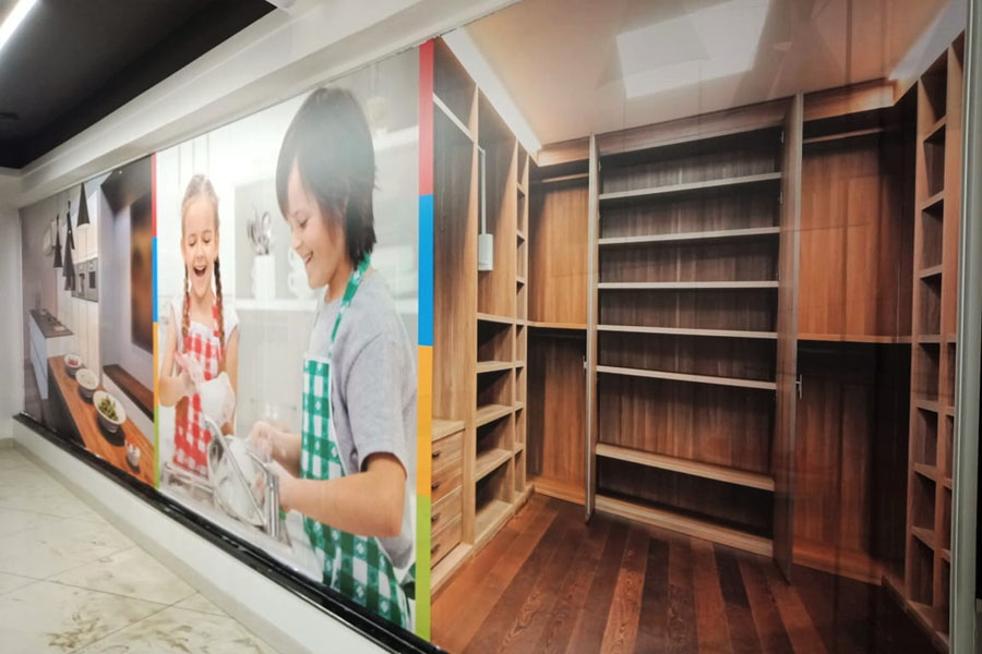A custom printed wallpaper showing images of small children fixed next to wooden shelves to enhance the interiors of a showroom
