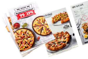 multiple thick rigid waterproof foam sheet printed menu cards of hotel spread out to show images of pizzas pastas and other fast foods