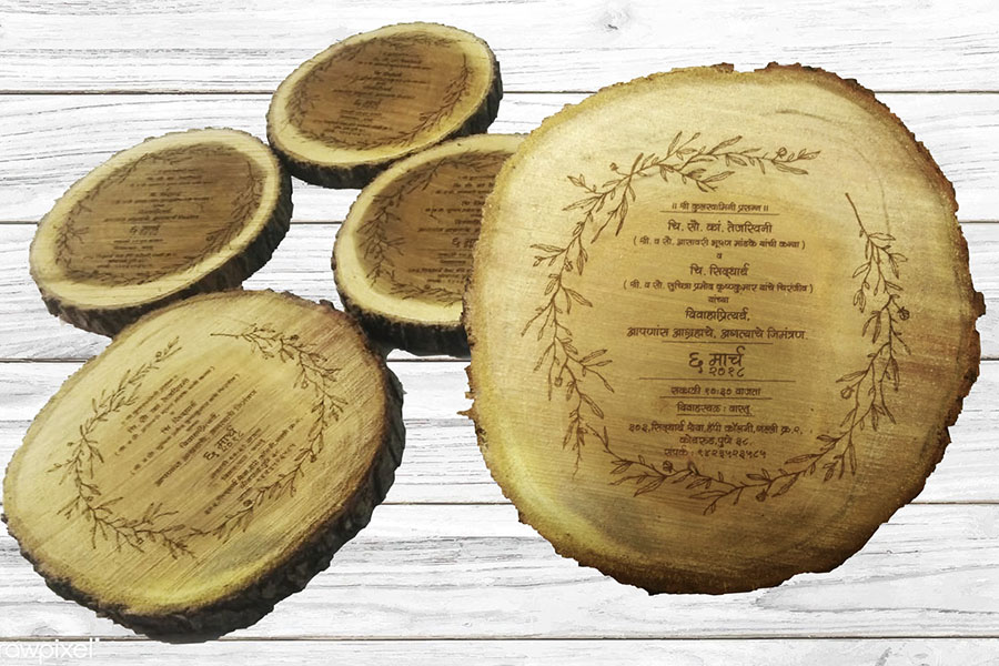 A wedding invite in marathi laser engraved on the cross section of a tree trunk