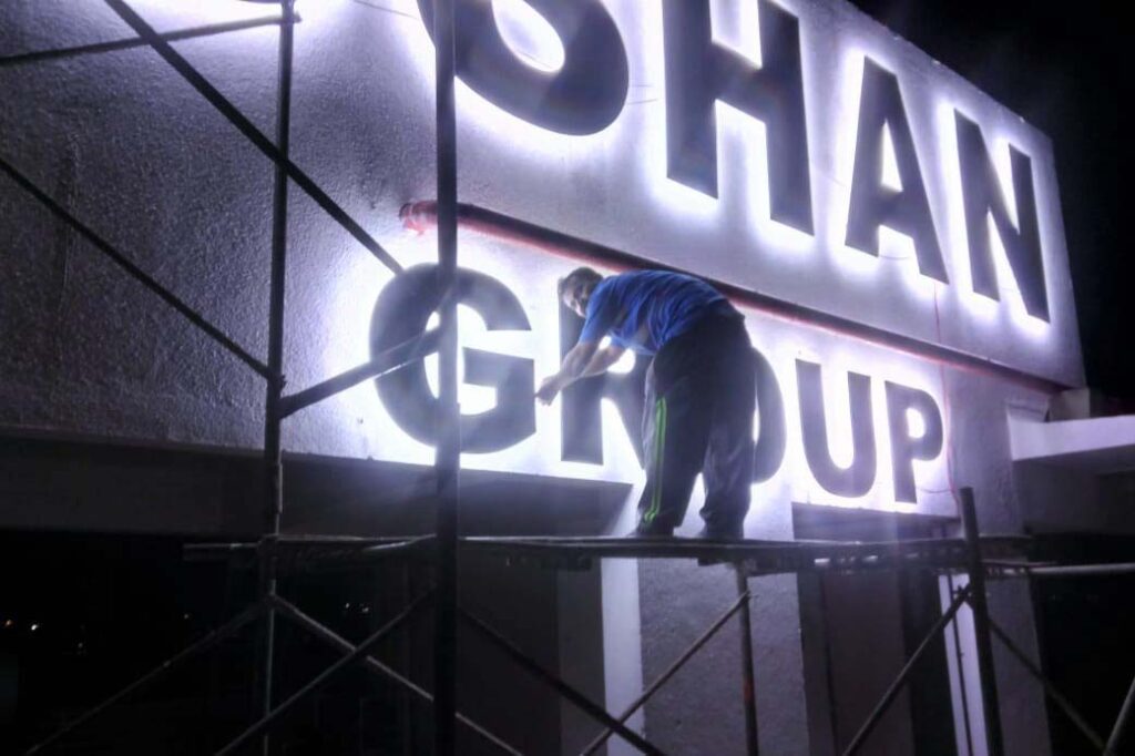 Metal letters almost the height of a man being installed as a sky sign on the side of a building. LEDs are give a letters a strong back glow