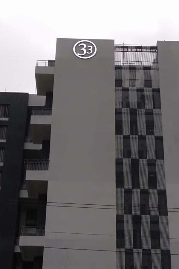 Logo in the shape of the number 33 fabricated from acrylic and metal letters glowing with LEDs and installed as a sky sign on the side of a tall residential building