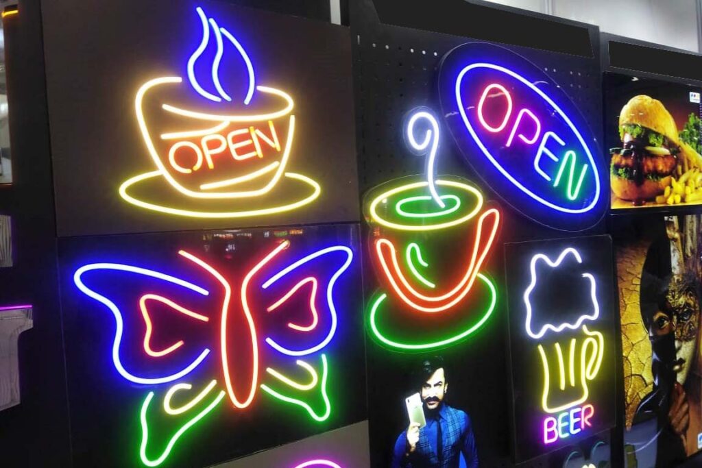 Multiple signs created in bright neon lights spelling out the words open and beer. Neons are all of different colors