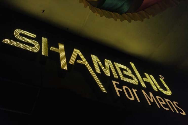 Gold metal letter sign board for the Shambhu Saloon with thousands of open dot LEDs on top