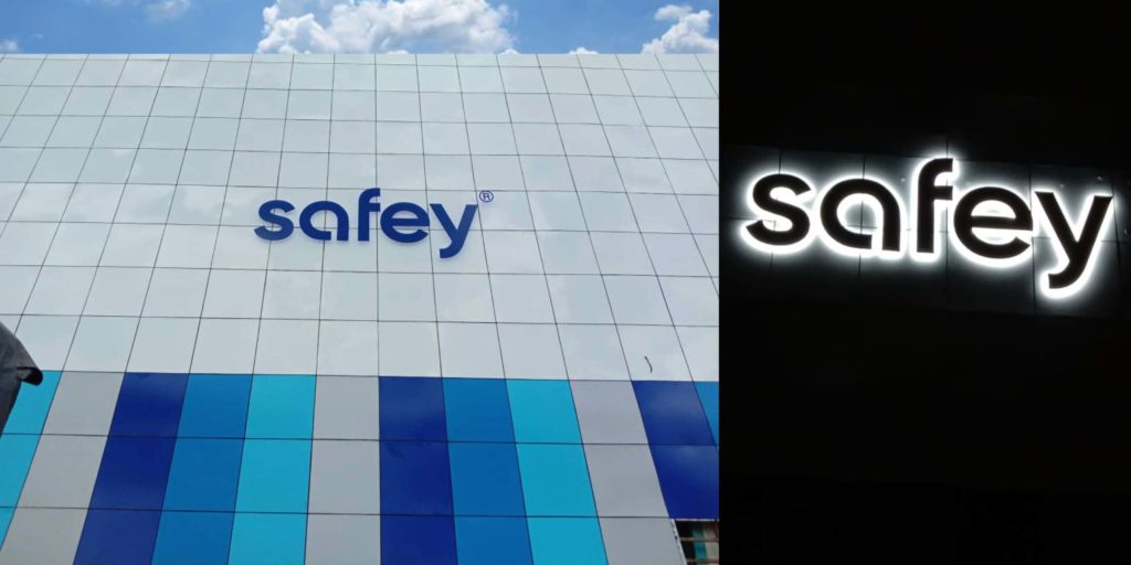 Day and night view of a metal letter sky sign for the Safey company fixed on the side of a very tall building