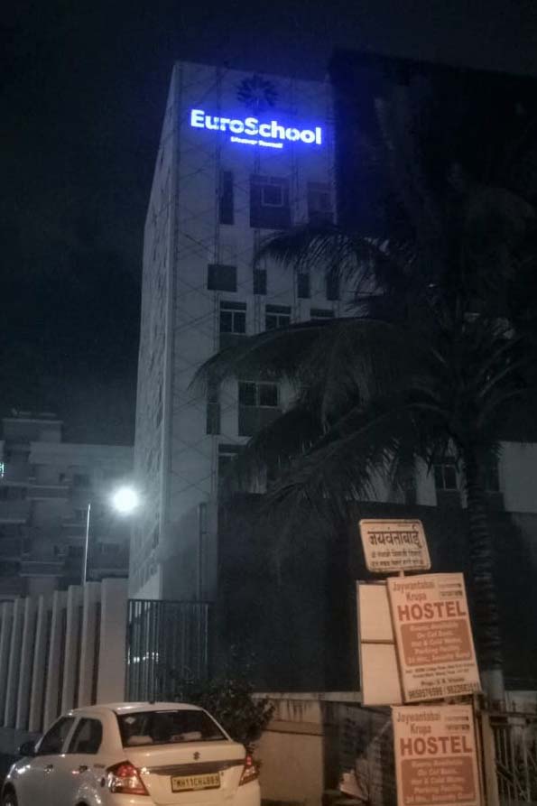 Night view of a glowing sky sign made from weatherproof acrylic and installed on the side of a tall building