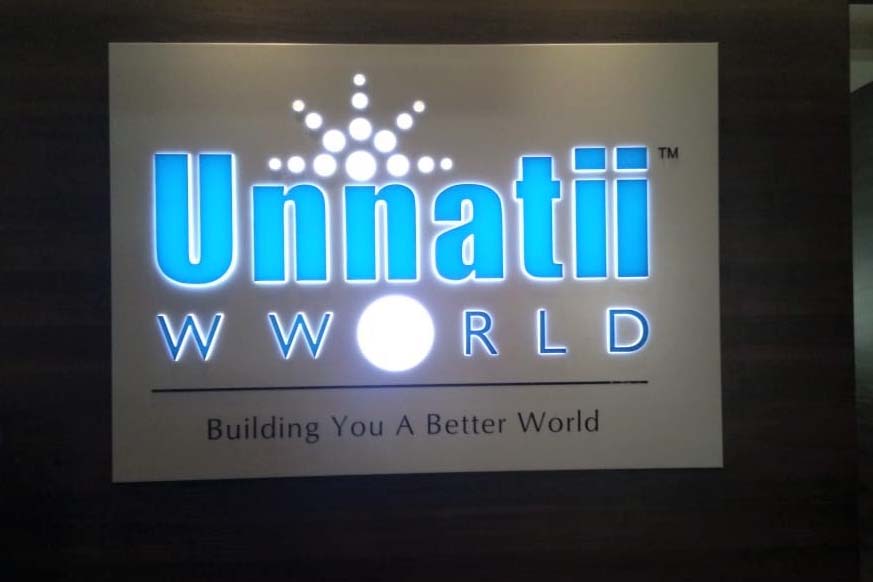 White aluminium composite board with incut acrylic letters for the Unnati world shop sign board. The sign is lit up with blue and white colored LED modules