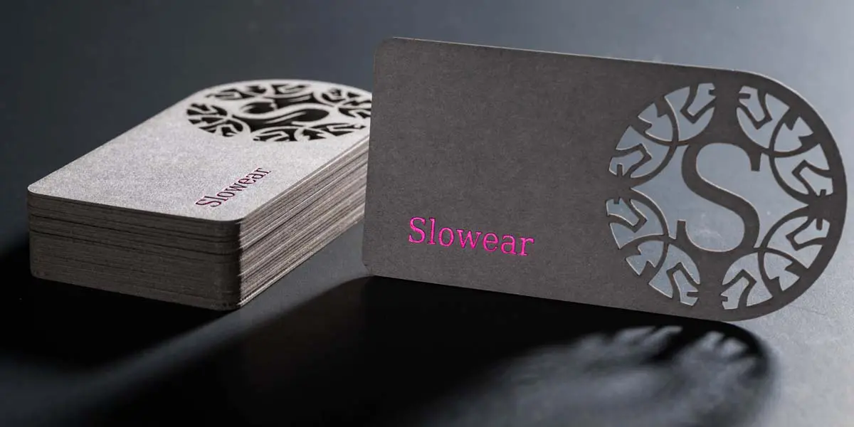 stack of laser cut business cards with a company logo cut through thick textured card paper