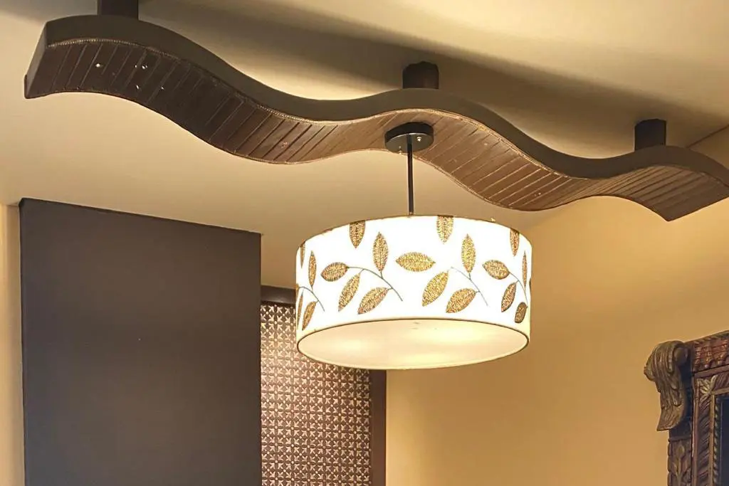 Here is a personalised lampshade suspended from the ceiling and carrying a custom design. A canvas print of a leaf pattern is wrapped around a hollow cylinder containing bright lights.