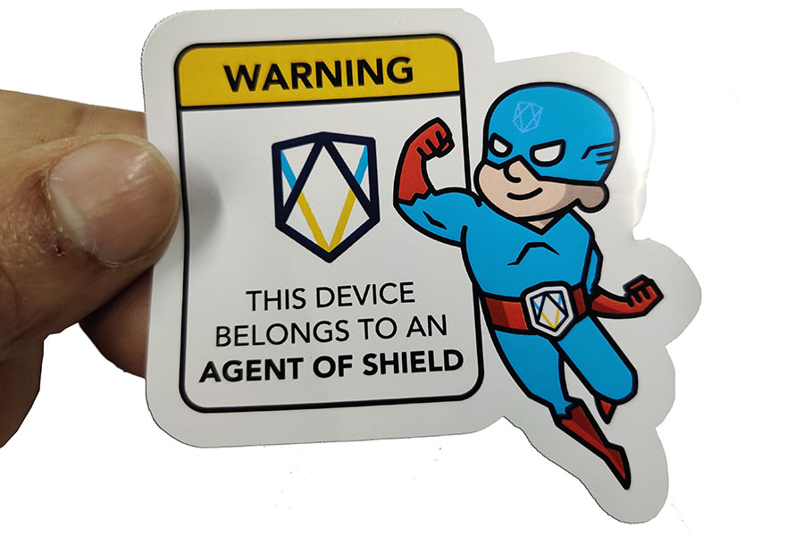 A non tearable plastic die cut sticker in the shape of a superhero cartoon held up for display