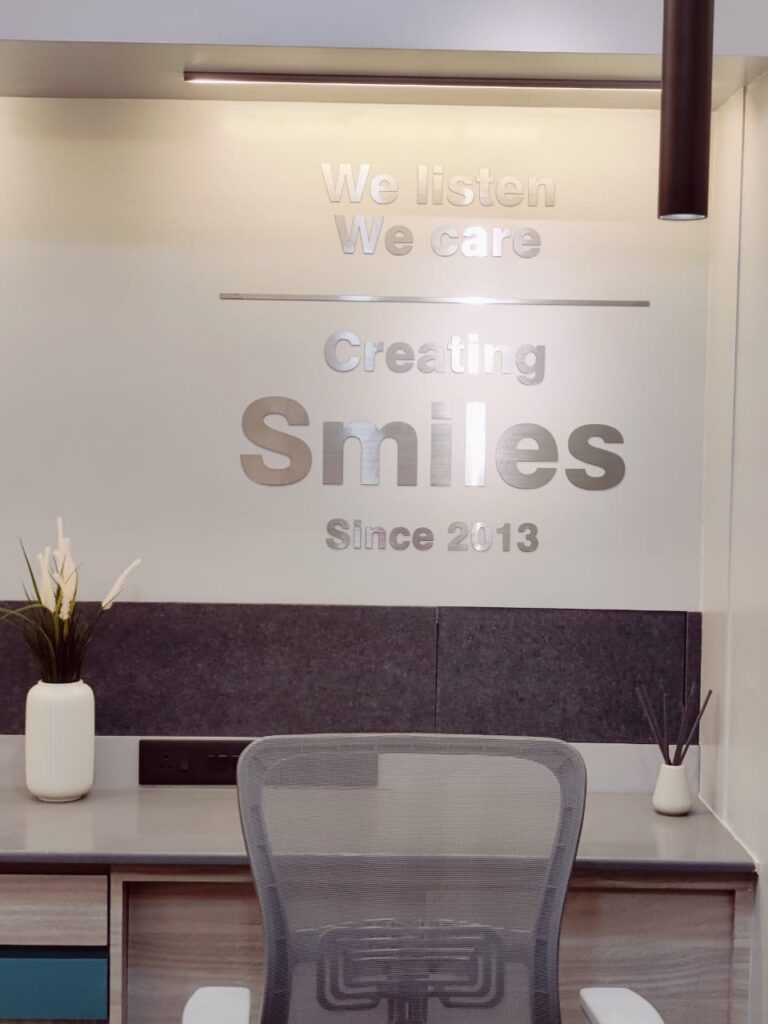 Slogan of a dental clinic made from brush finish silver acrylic letters pasted directly on the wall