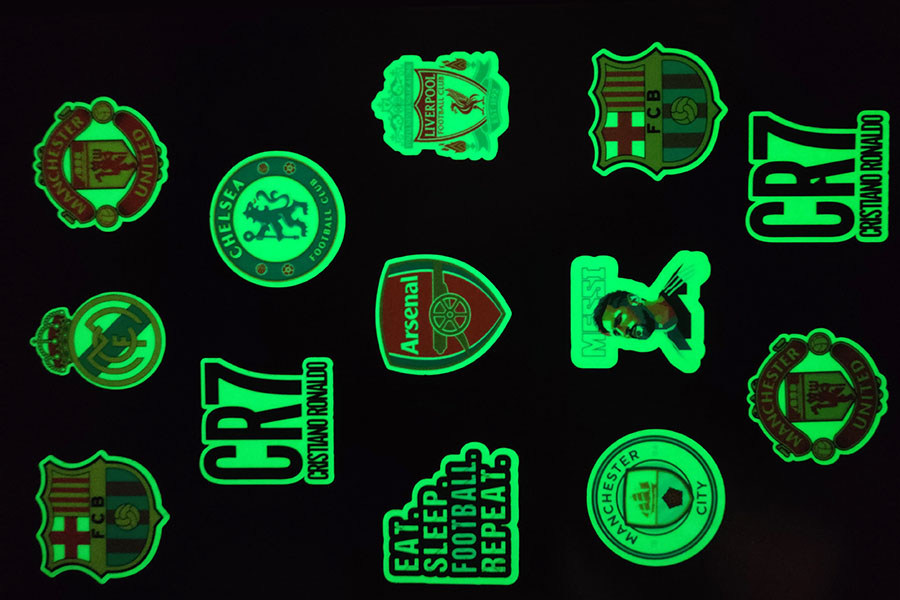 Glow in the dark die cut stickers of different shapes that are emitting a greenish light when seen at night