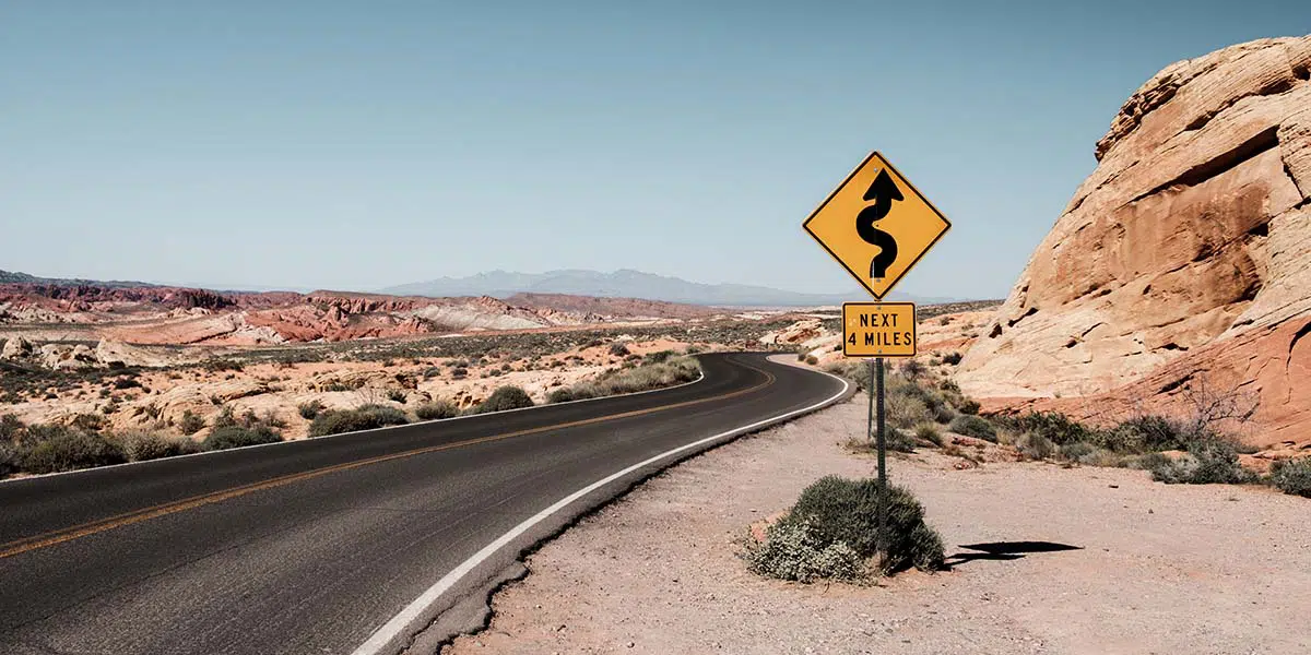 Road safety sign cautioning a motorist about a sharp curve ahead