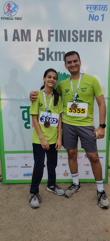 A father and daughter posing in front of a selfie stand after completing a 5 Km marathon run