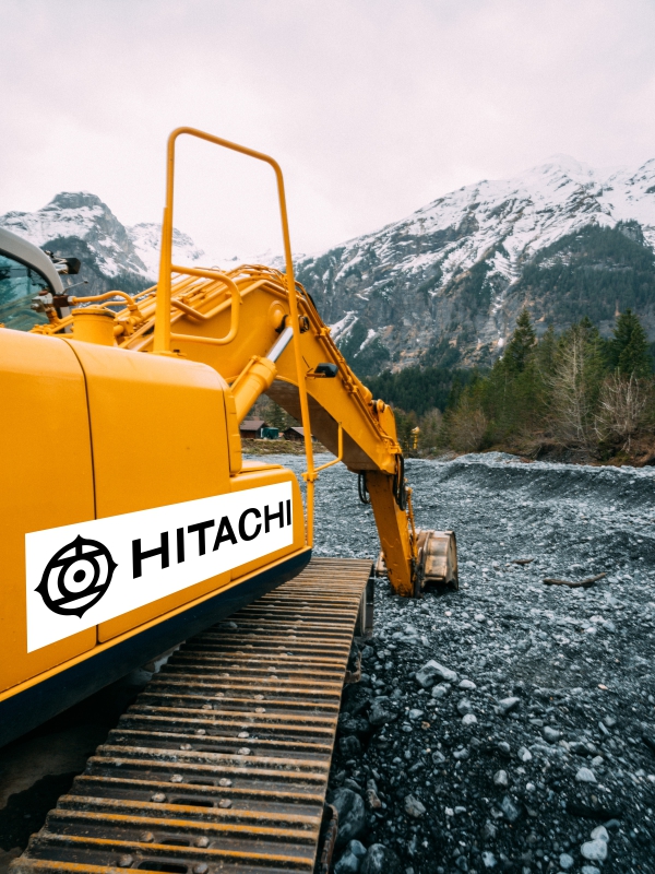 a perspective view of earth moving machinery shifting the rubble with snowy mountains in the background marked by the Hitachi company logo using temperature resistant stickers