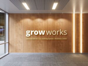 White colored laser-cut acrylic logo for the Grow Works company fixed on a wooden wall inside their office