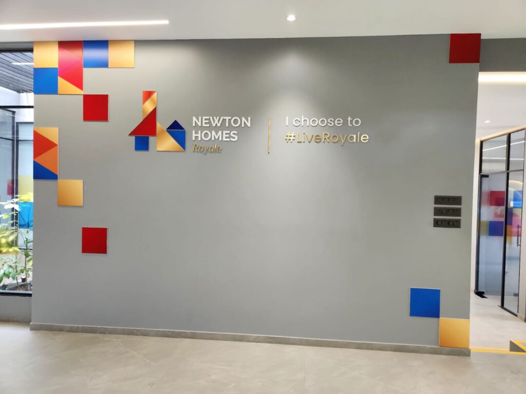 Colourful acrylic sheets laser-cut in the shape of the ‘Newton Homes’ company logo and pasted on a wall inside their corporate office