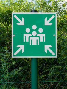 An emergency assembly sign installed on a metal fold to direct people to safety in case of a emergency