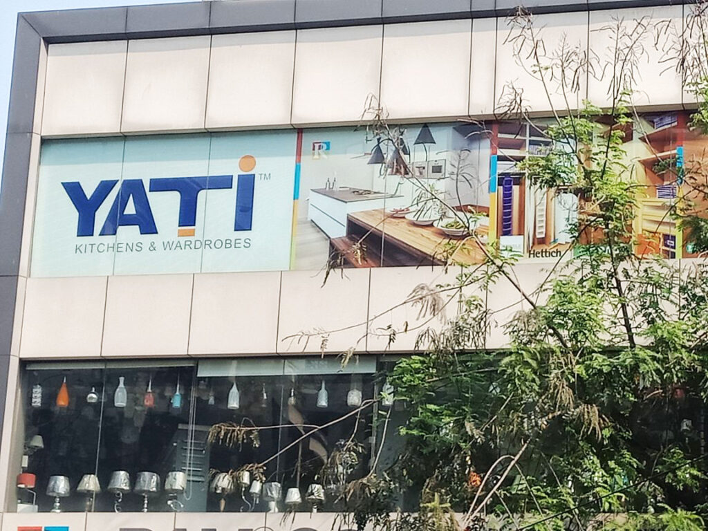A large glass film covering the front face of a huge building with the corporate logo and product images printed on the same