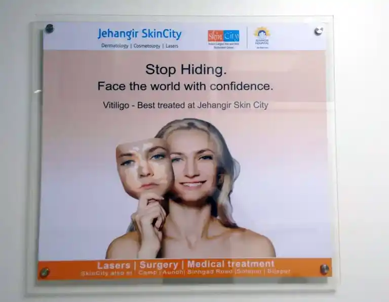 Front view of an acrylic sandwich poster panel installed on a wall inside a clinic with stud cap screws on the four corners