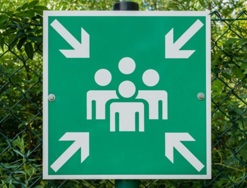 An emergency assembly point signed installed on a metallic aluminum composite panel sheet fixed on a pole installed in an outdoor location