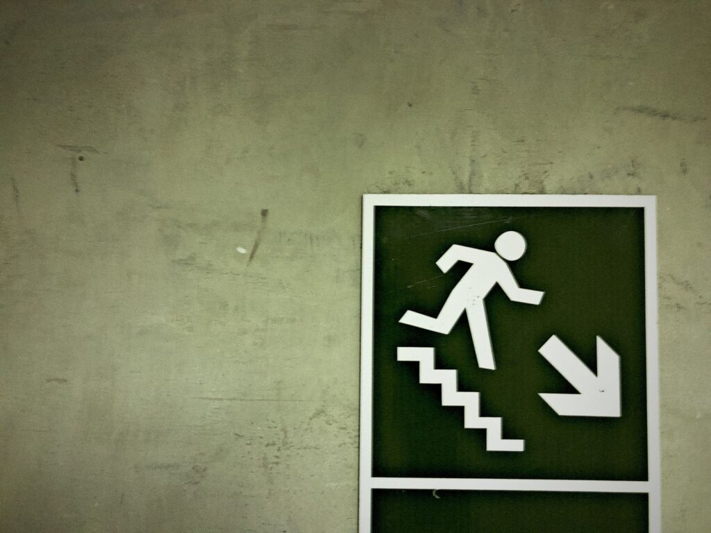 a Emergency exit sign directing people to an escape route down the stairs fixed on a wall