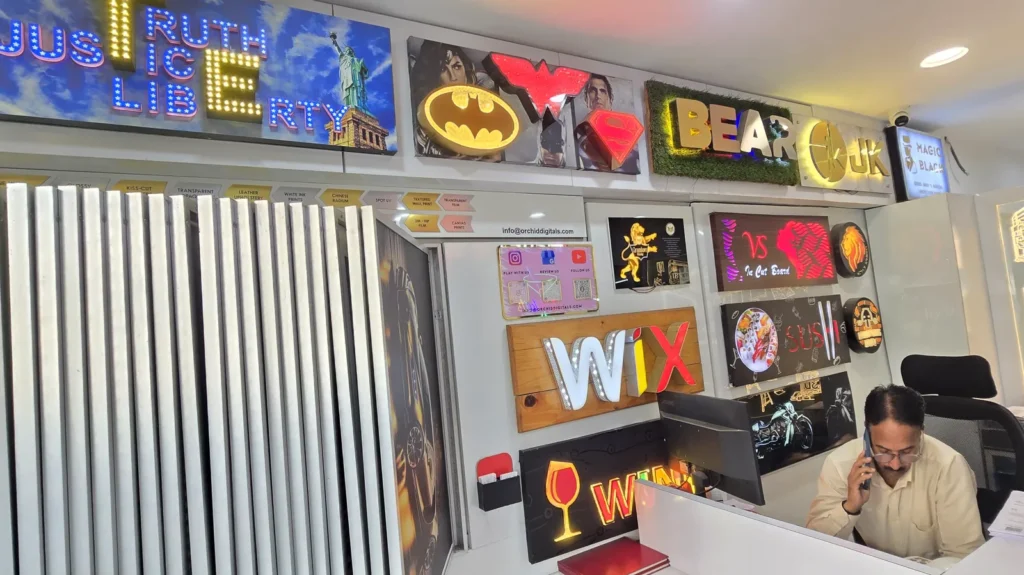 Accounts desk at Orchid Digitals beside the media sample panels and a wall of LED sign samples