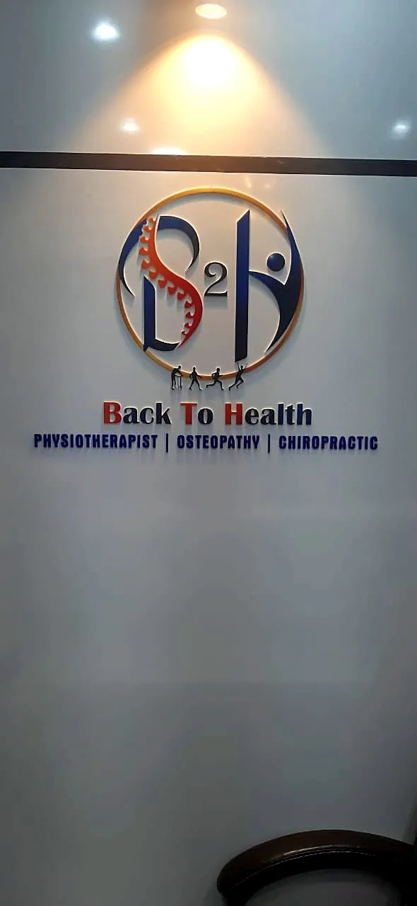 Back To Health logo in 3D acrylic fixed straight on the clinic wall: spine monogram, small figures and fine text, no base plate