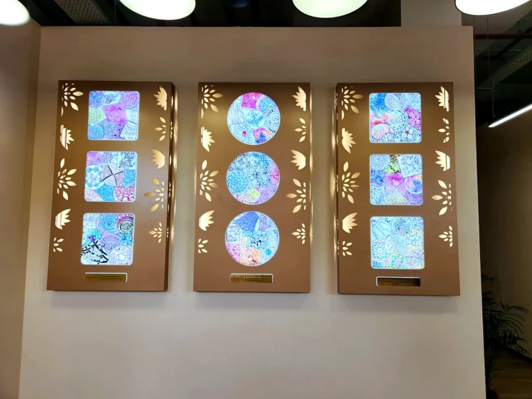 Three backlit rose-gold art panels with enlarged pattern drawings on a reception wall