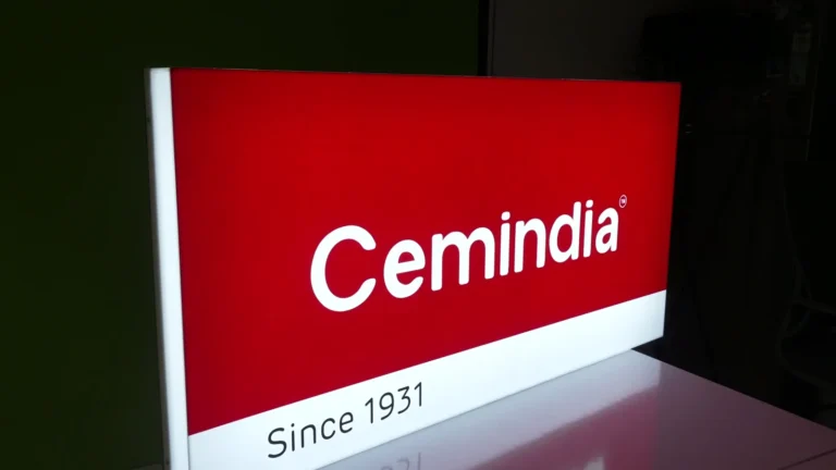 The Cemindia 2D acrylic light box lit up: a flat red printed face with the white Cemindia logo and a white Since 1931 band, its white acrylic side glowing