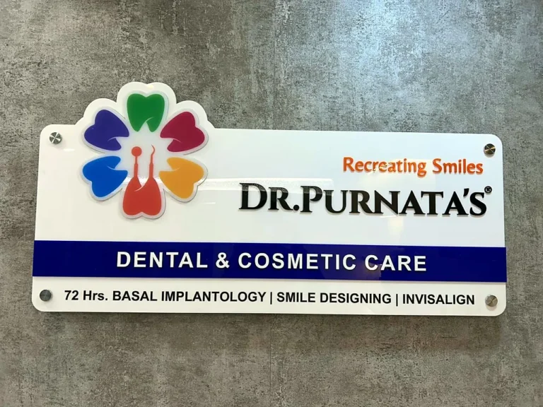 Dr Purnata’s Dental & Cosmetic Care entrance board: colourful tooth-flower logo and name on white acrylic with standoffs