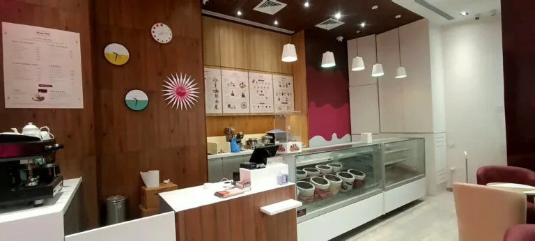 Behind the counter: four acrylic clocks on the wooden wall, the menu boards, and the vinyl-wrapped cupboard with its melting-ice-cream design