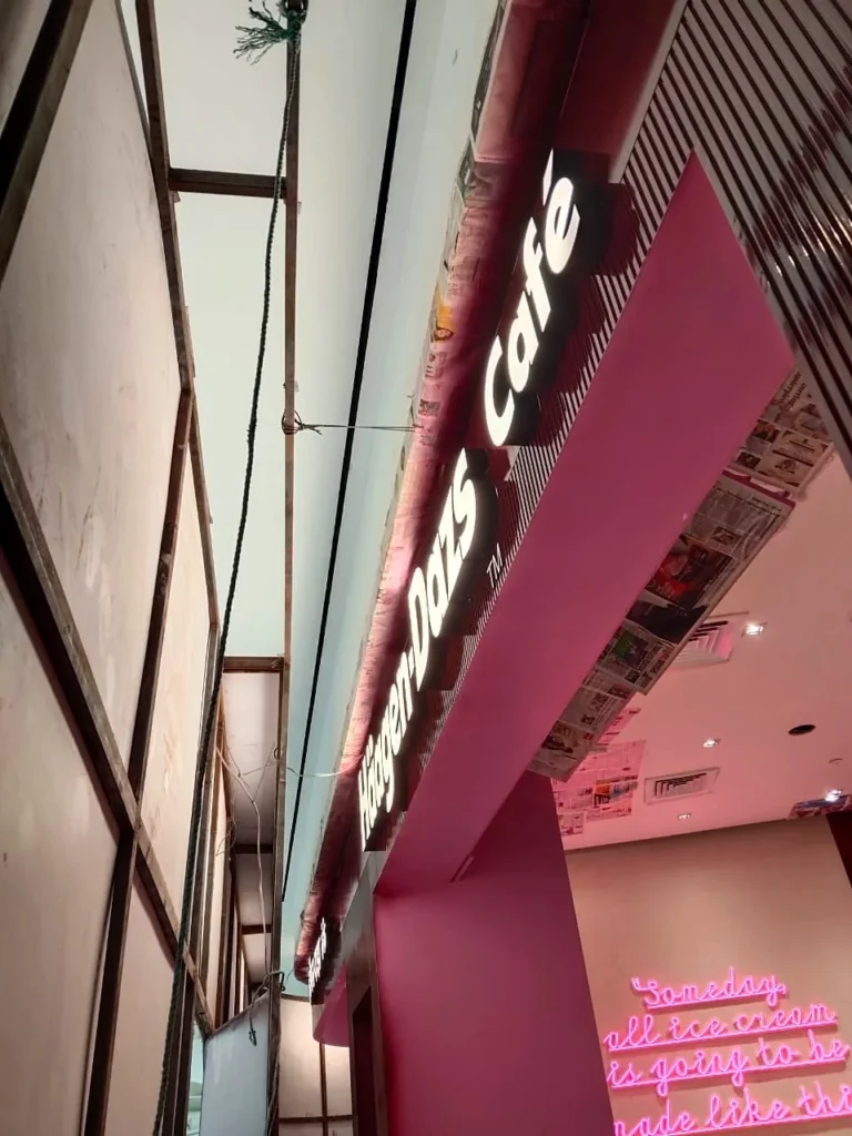 Installation night: the Häagen-Dazs Café letters going up on the curved fascia, walls still masked