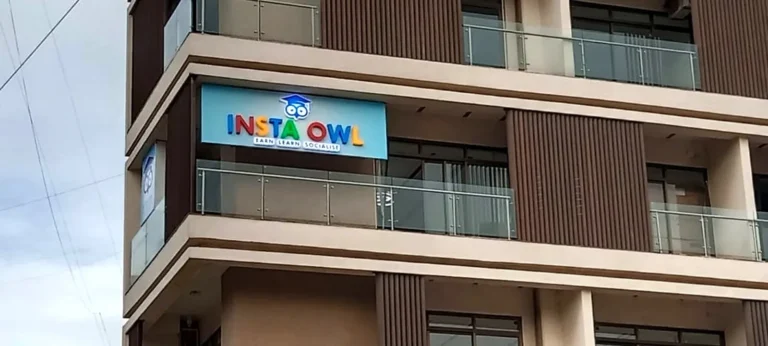The Insta Owl board at the front edge of a balcony high on an office building, Pune: 3D LED acrylic letters on a white-to-blue gradient panel