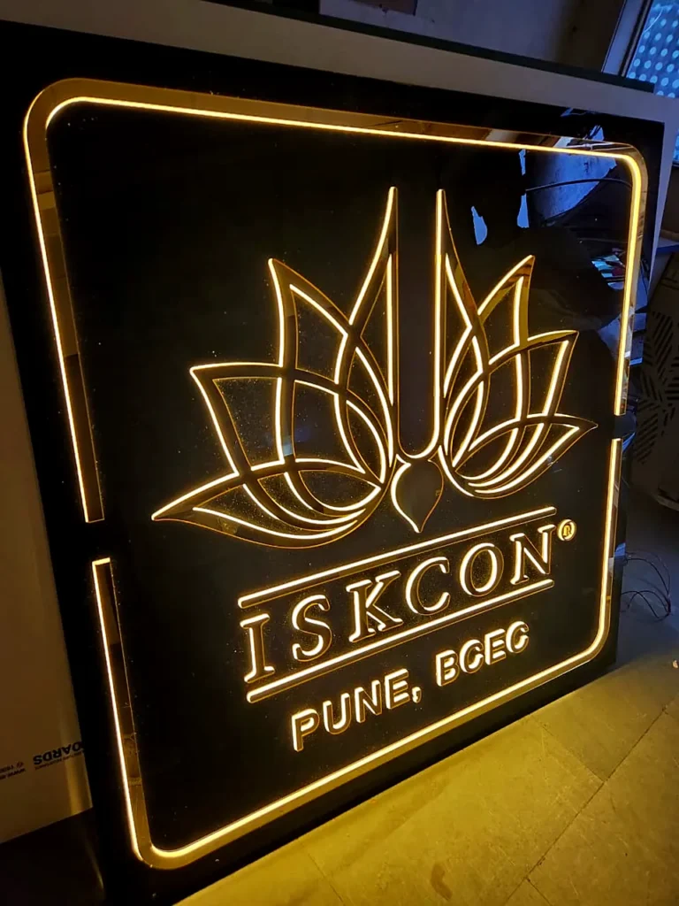 ISKCON Pune BCEC gold acrylic logo board glowing at night