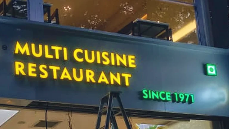 Close-up at night: the lit yellow Multi Cuisine Restaurant letters, now spelt correctly, and Since 1971 in green on the Jayashree fascia, Viman Nagar