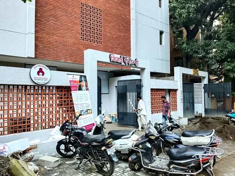 Jijai Residency frontage with the building name over the gate and the round hostel logo