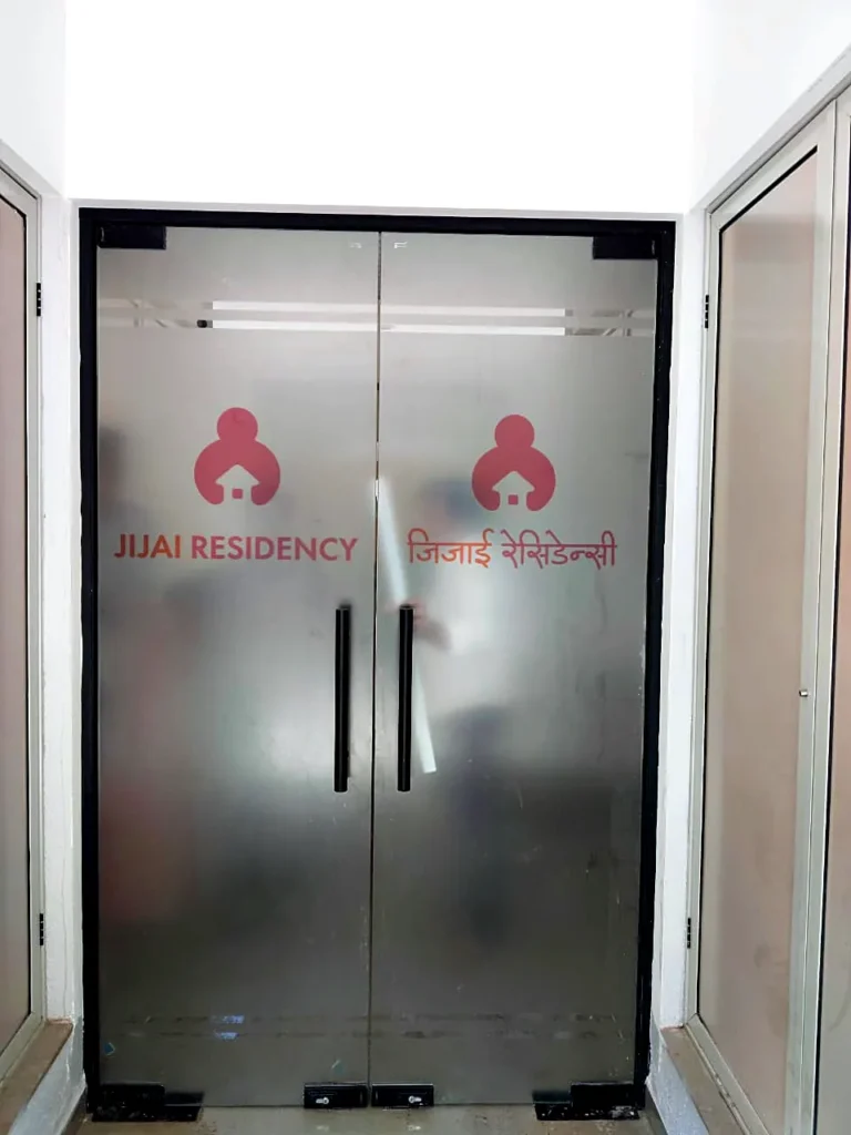 Jijai Residency logo printed on frosted film on a pair of glass entrance doors, English and Marathi